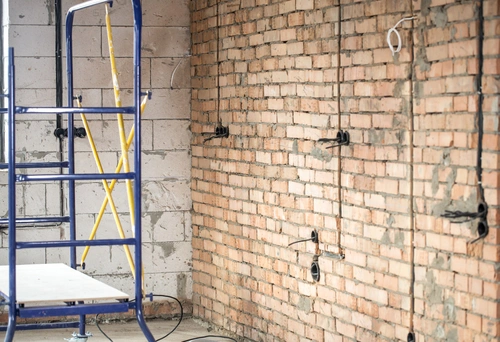 Altbau-Wohnzimmer während der Sanierung mit roher Ziegelwand und Gerüst